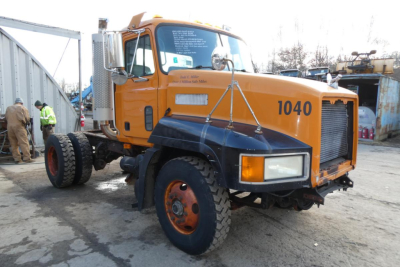 Truck front view of a yellow/orange 1998 Mack CH612 with number 1040 on the door, plow category, stock number 1010255.