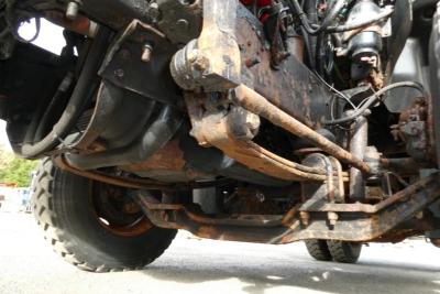 Underbody view of a 1998 Mack CH612 truck showing rust on frame and suspension components, drivetrain, and steering linkage