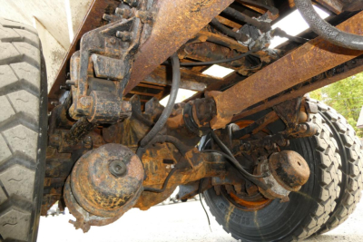 Truck rear axles and suspension showing rusted air springs and drive axles undercarriage with leaf springs and wheels.