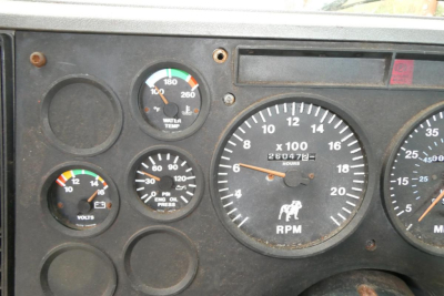 Dashboard panel of a Mack truck showing RPM gauge and battery/voltage indicators.