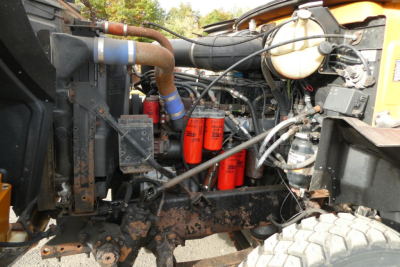 Mack CH612 engine bay with hoses, filters, and components; view shows orange filters, radiator hoses, and wiring in a used plow truck.