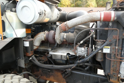 Machinery engine bay showing turbocharger, hoses, and label stickers in a Mack CH612 plow truck.