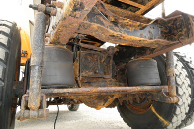 Rear undercarriage of a Mack CH612 truck showing suspension and twin air springs with rusty frame members and large rear tires.