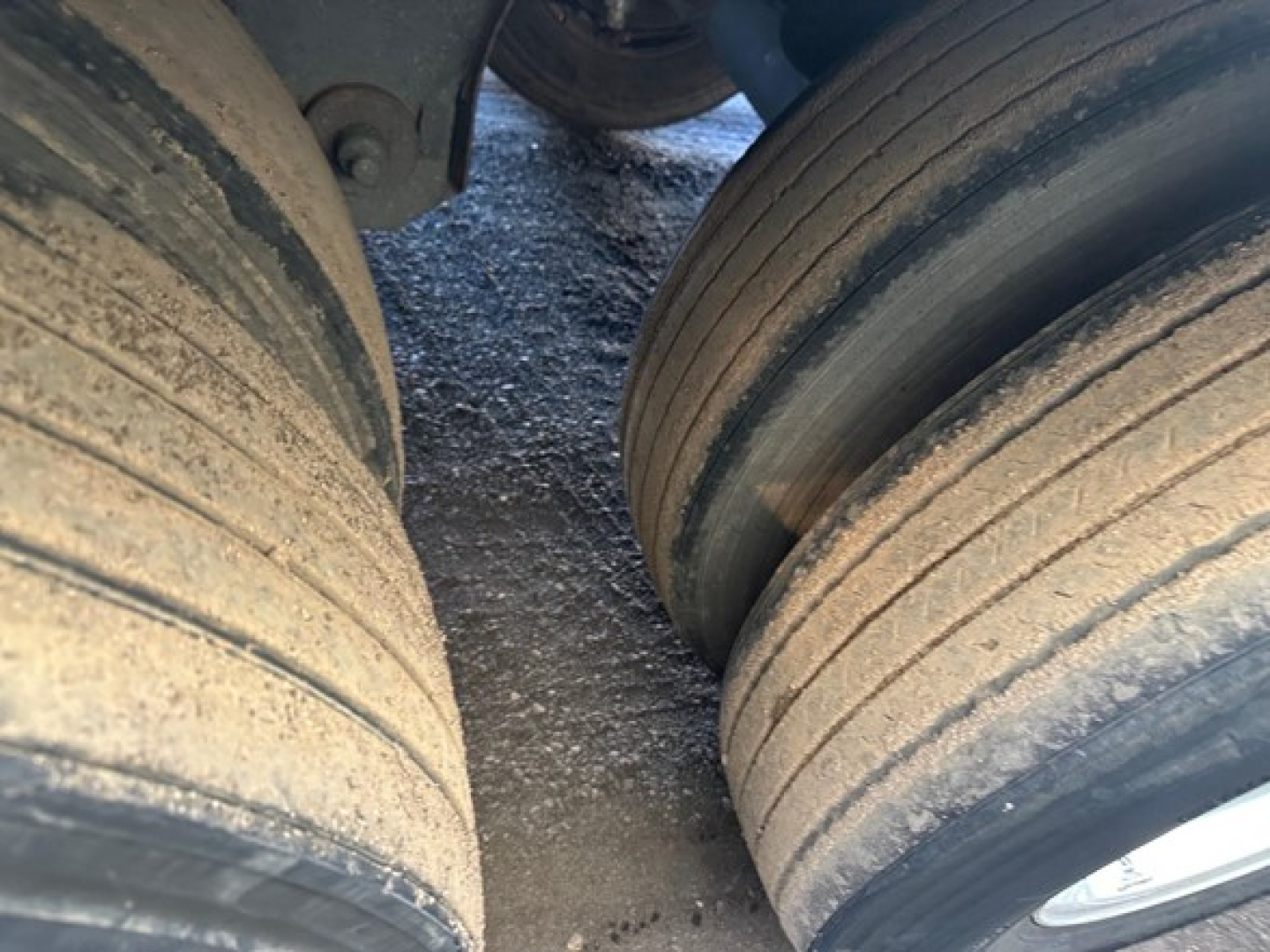 Trailer wheels and dual-tire configuration showing worn tread on outer tires and dust on wheels; part of a refrigerated trailer undercarriage.