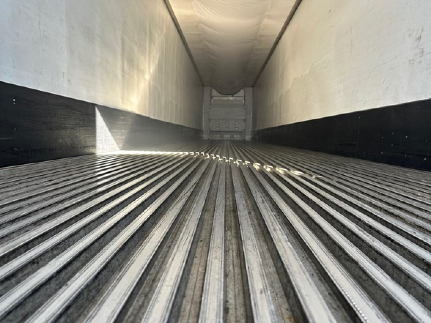 Interior of a refrigerated trailer trailer floor with ribbed steel and rear bulkhead, viewed from the front opening.