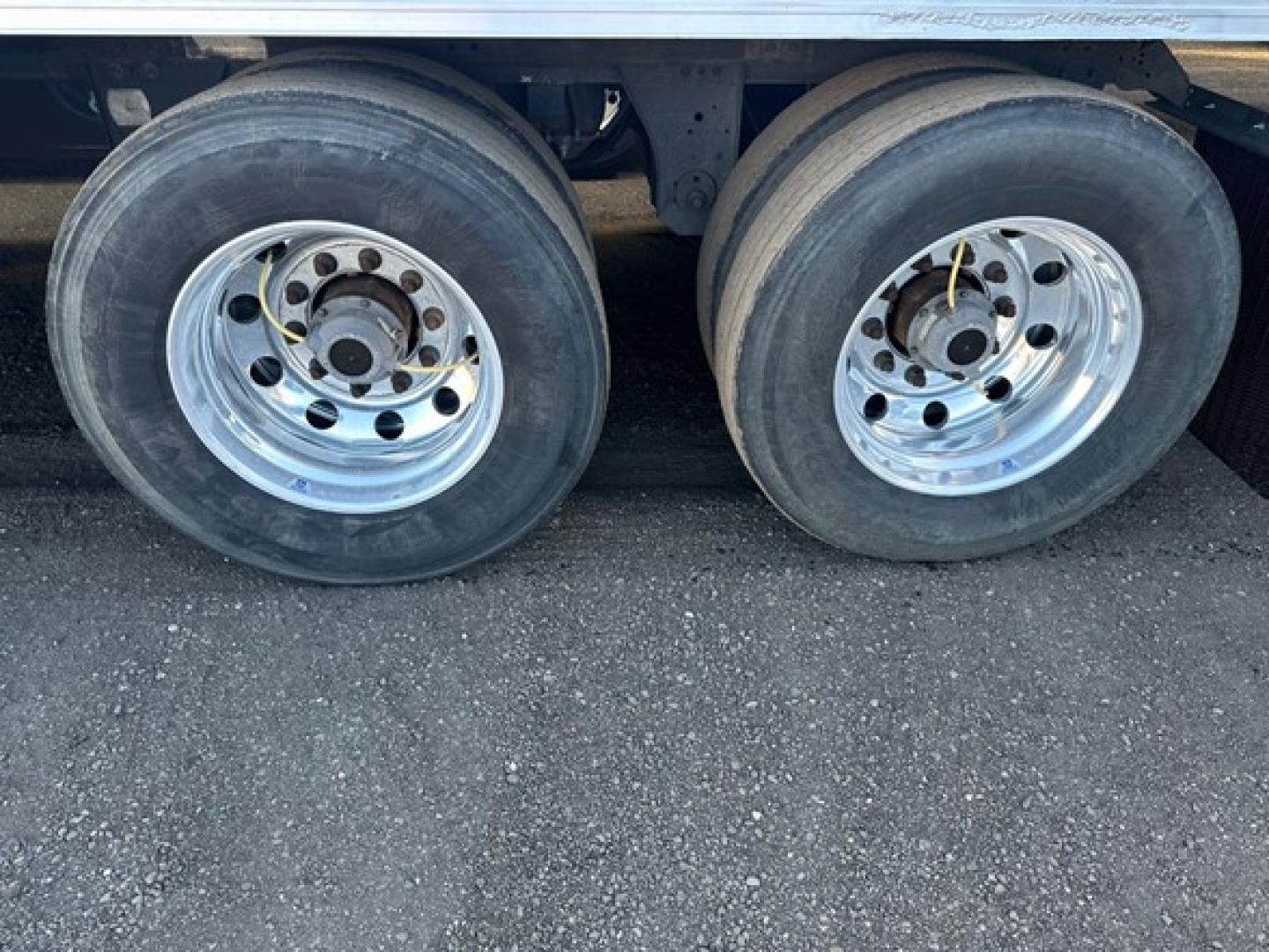 Dual rear trailer wheels with polished steel rims and black tires under a Utility 3000R reefer trailer side view.