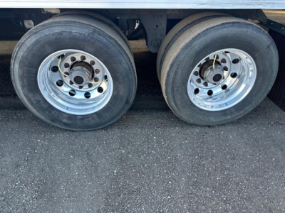 Dual rear trailer wheels with polished steel rims and black tires under a Utility 3000R reefer trailer side view.
