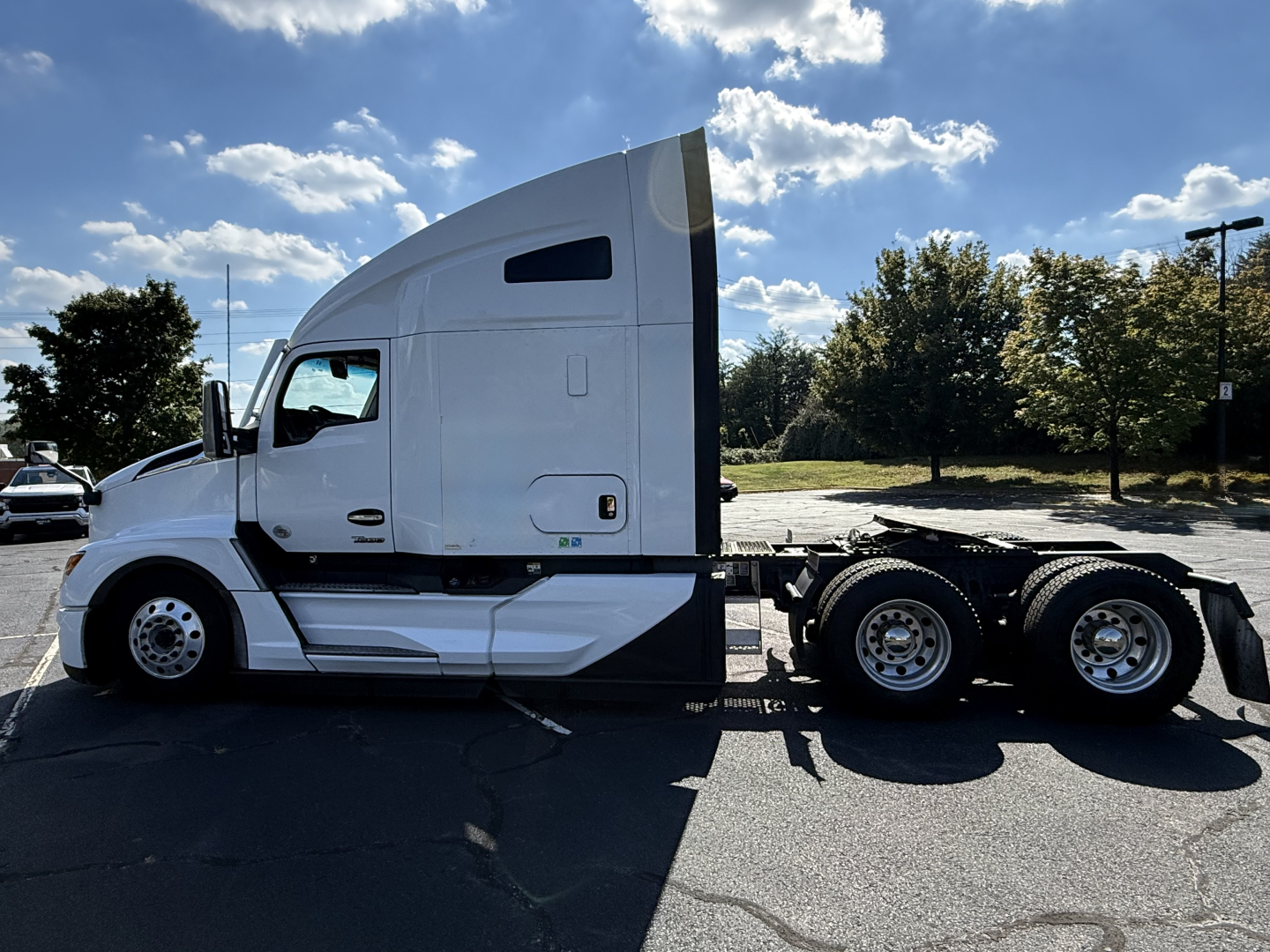 Kenworth T680 tractor side view showing sleeper cab, white paint, and rear axles under the chassis.