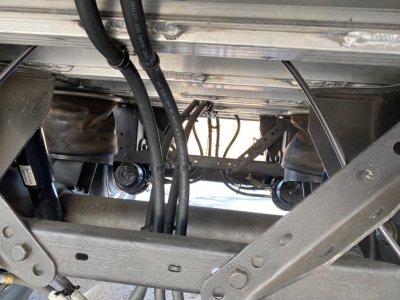 Trailer undercarriage showing frame rails and hydraulic lines in view beneath Mac Light Weight trailer.