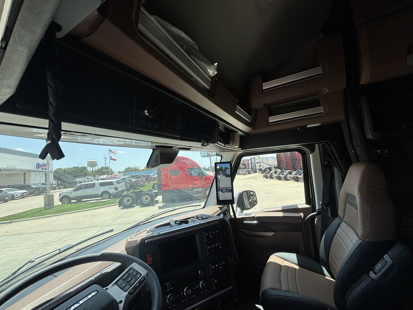 Truck cab interior view showing dashboard and overhead storage in a Mack PR64T76H sleeper cab.