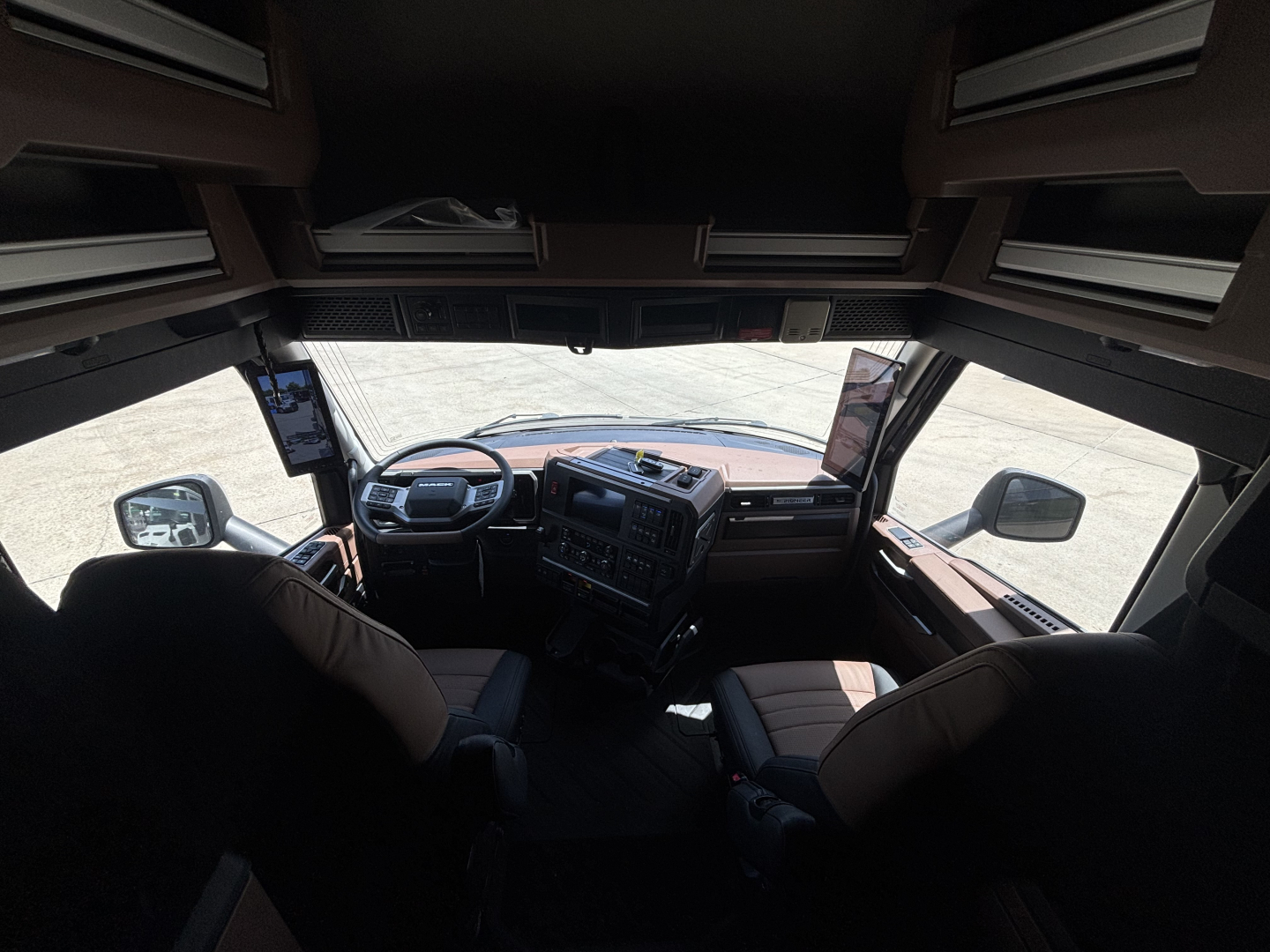 Mack PR64T76H truck cockpit interior showing dashboard, steering wheel, and overhead storage compartments.