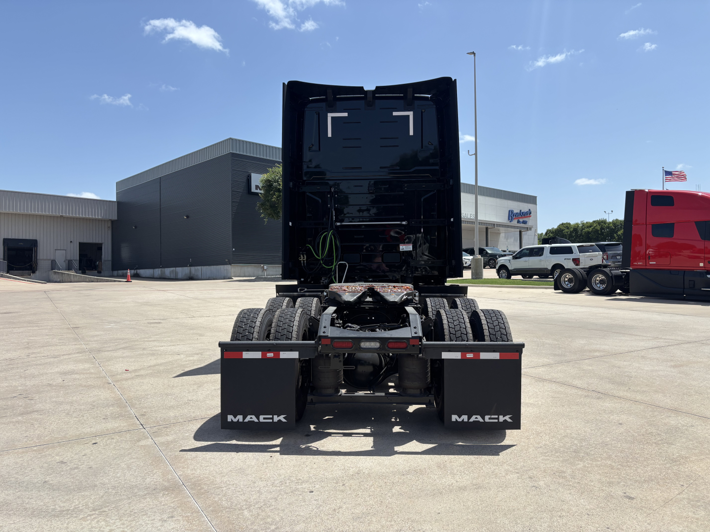 Rear view of a new Mack PR64T76H conventional sleeper truck showing the chassis and dual rear axles with mud flaps labeled ‘MACK’.