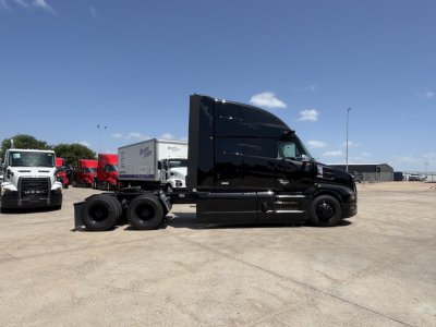 Side view of a black 2027 Mack PR64T76H tractor truck in a parking lot. No visible text on the truck exterior.