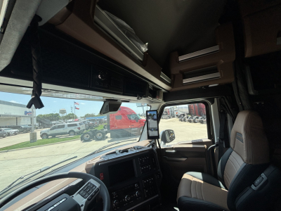 Truck cab interior view showing dashboard and overhead storage in a Mack PR64T76H sleeper cab.