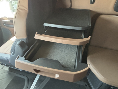 Mack PR64T76H cab interior showing open overhead storage compartments with beige trim in the back seat area.