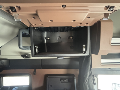 Mack PR64T76H sleeper cab interior showing open overhead storage compartment and dashboard area with beige trim.