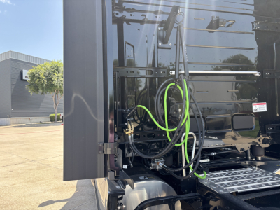 Mack PR64T76H truck rear with exposed cab connections and bright green hoses, view of side step and fuel lines.