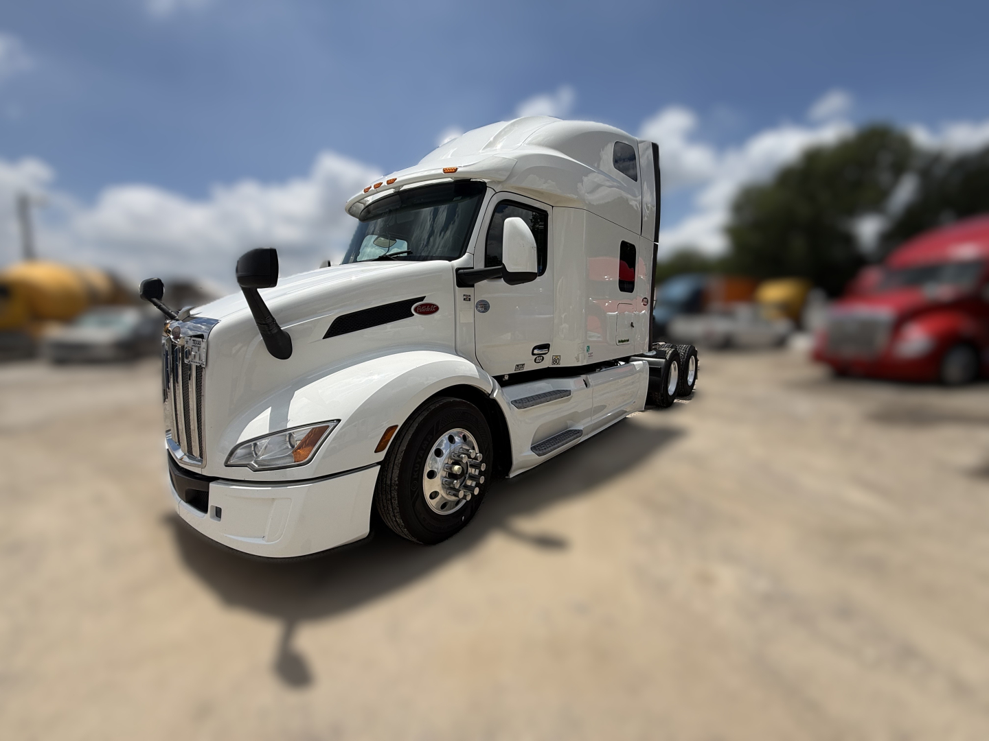 Peterbilt 579 conventional sleeper truck in white, front three-quarter view, showing chrome grille, side mirrors, and large sleeper cab.