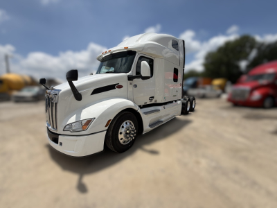 Peterbilt 579 conventional sleeper truck in white, front three-quarter view, showing chrome grille, side mirrors, and large sleeper cab.
