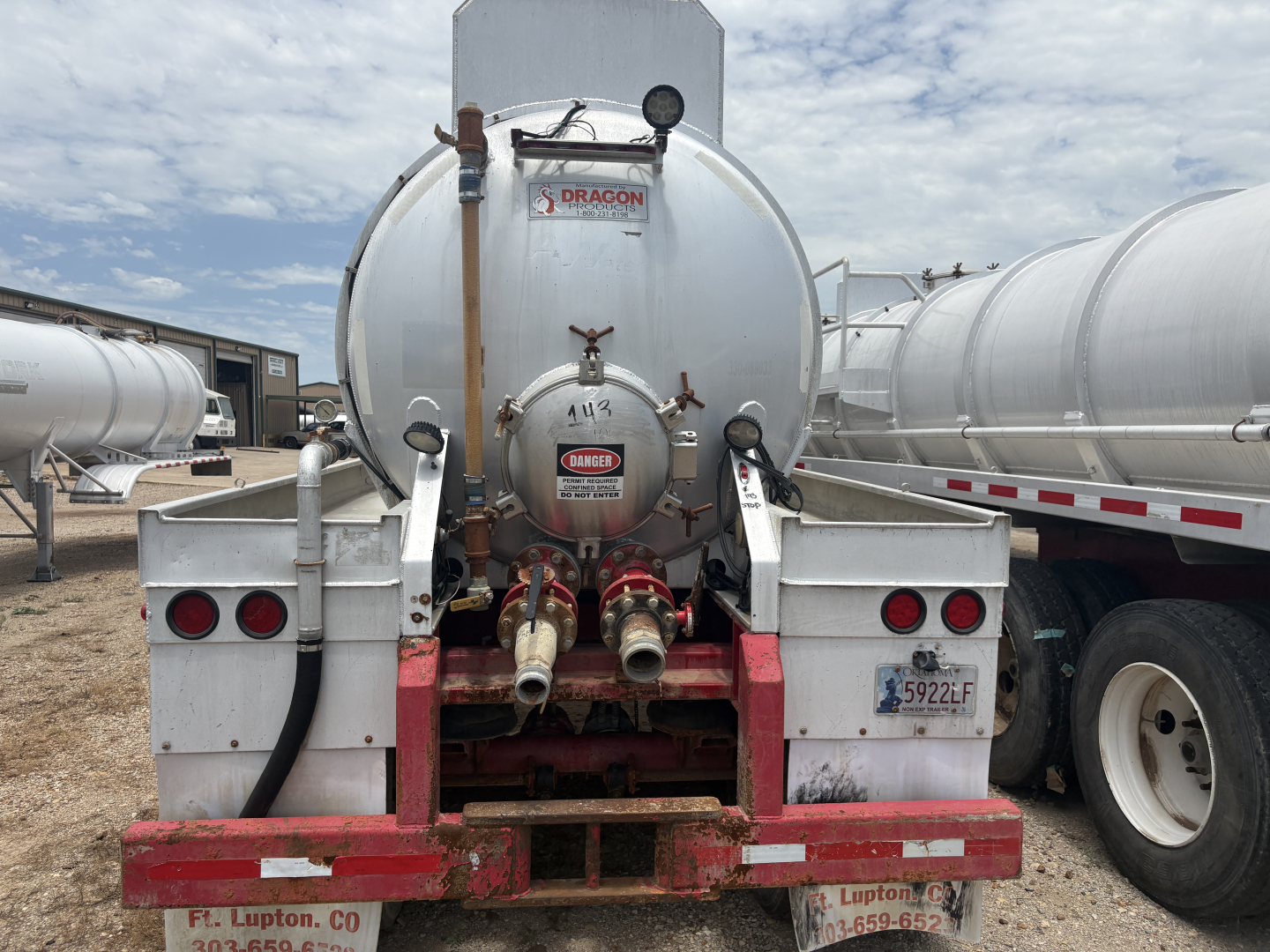 Dragon vacuum trailer rear showing dual outlet hoses, circular tank with Dragon label, taillights, bumper, and bumper signage plate.