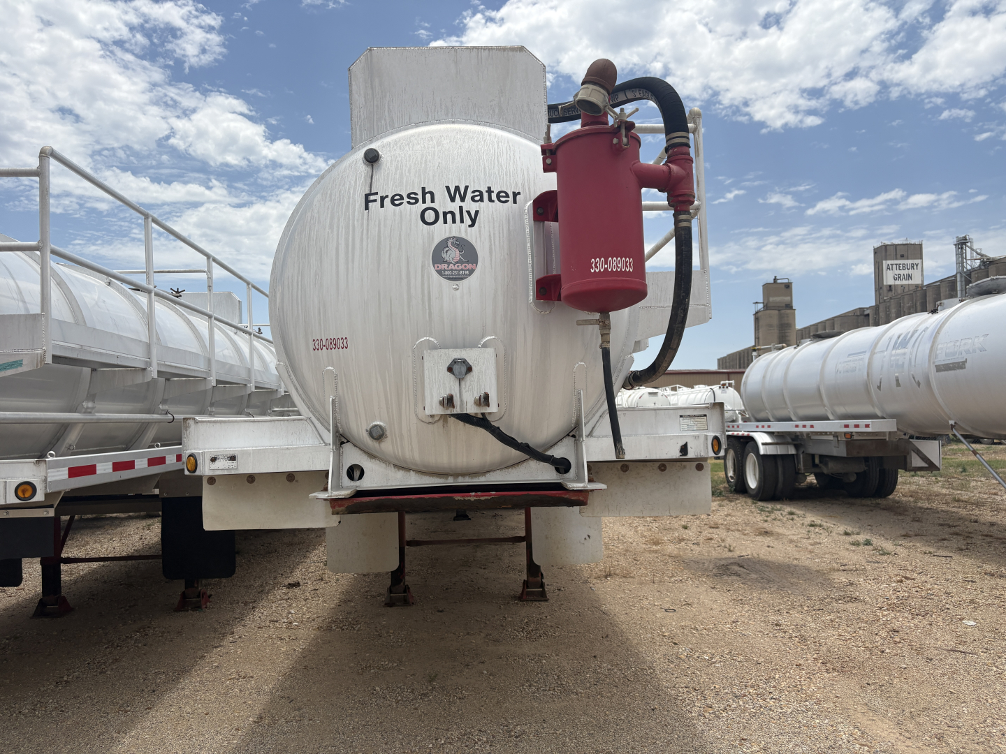 Tank trailer with circular stainless tank labeled Fresh Water Only and a red pump on the front showing hoses and support frame.