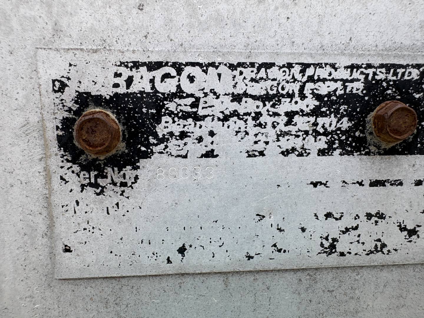 Plate showing faded label with partially readable 'BAG' and screws, worn metal with peeling paint and rust spots.
