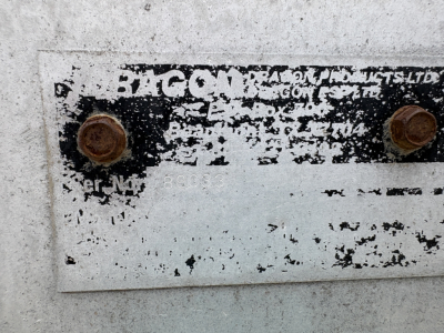 Plate showing faded label with partially readable 'BAG' and screws, worn metal with peeling paint and rust spots.