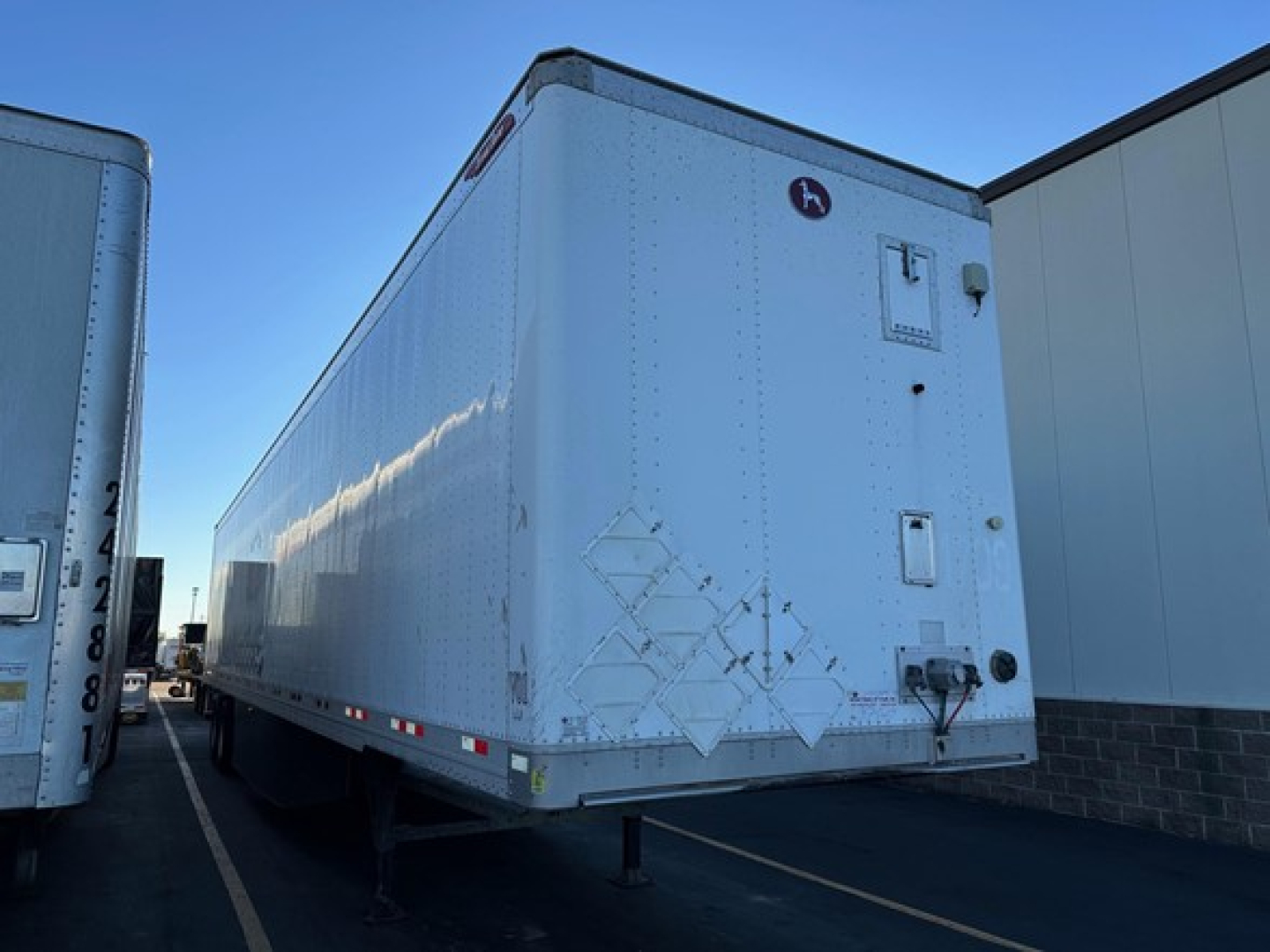 Truck trailer in a lot showing rear and side, 2017 Great Dane Champion trailer with diamond plate corner guards and latching doors.