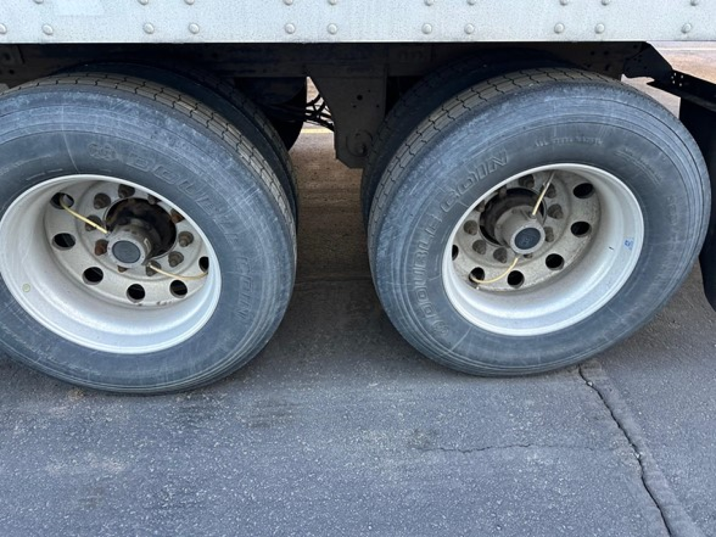 Dual rear trailer wheels and tires viewed from side showing rims and wheel hubs.