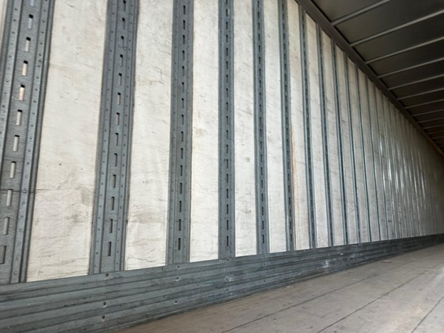 Trailer interior showing vertical metal wall rails and sidewall panels in a loading trailer.