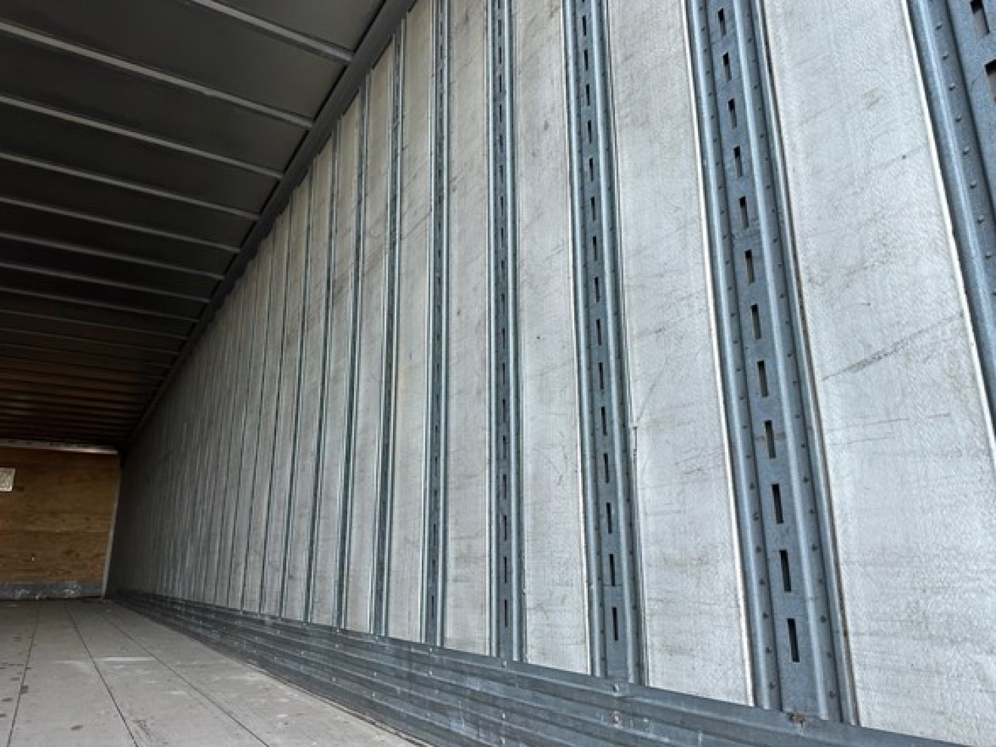 Trailer interior wall with vertical metal studs and ribbed support.
