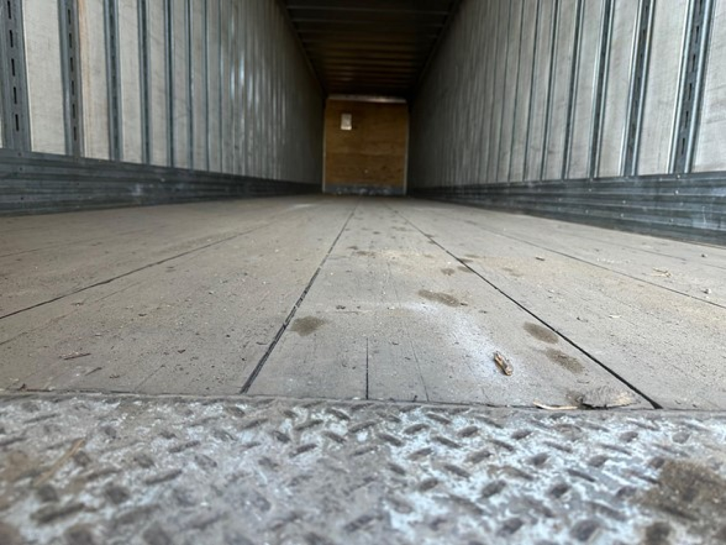 Interior trailer floor and rear entry showing cargo trailer deck with metal side walls, wooden bulkhead at far end, Great Dane Champion trailer model interior view.