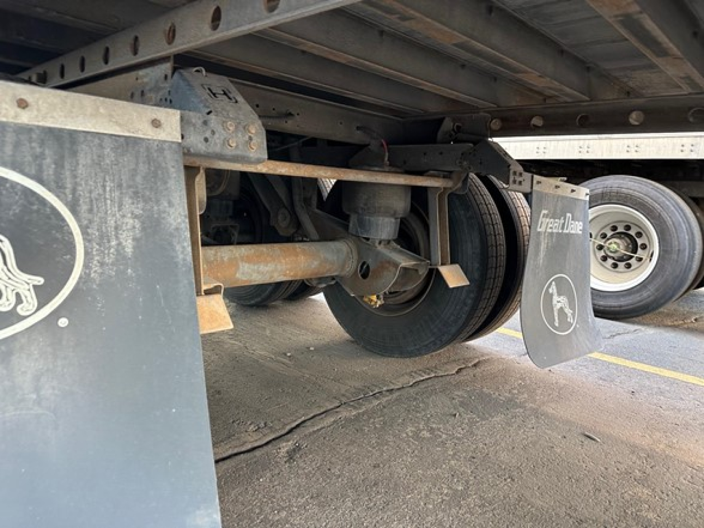 Trailer undercarriage showing wheel, suspension, and mud flaps with Great Dane branding.
