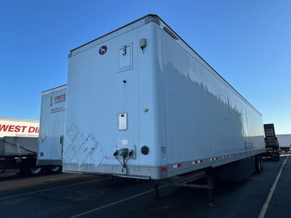 Great Dane Champion trailer in a parking lot showing rear and side view with support legs lowered and reflective trailer side panels.