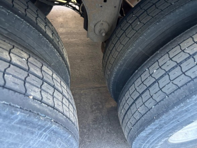 Rear dual axle trailer tires and leaf spring undercarriage viewed from between the wheels.