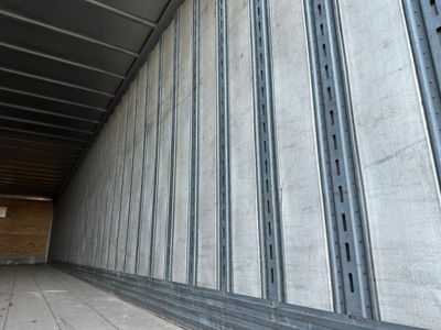 Trailer interior wall with vertical metal studs and ribbed support.