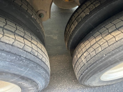 Two trailer tires on a Great Dane Champion trailer undercarriage showing tread patterns and gravel on the ground.
