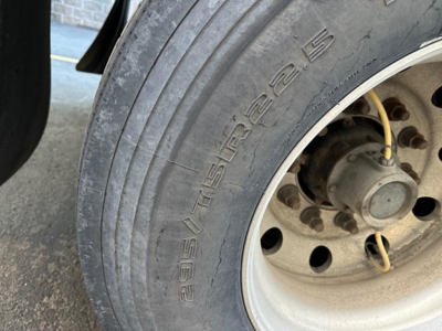 Great Dane Champion trailer wheel showing oversize tire with brand name 'Goodyear' or 'Spare' (text on sidewall blurred) and wheel hub with bolts and brake components visible.
