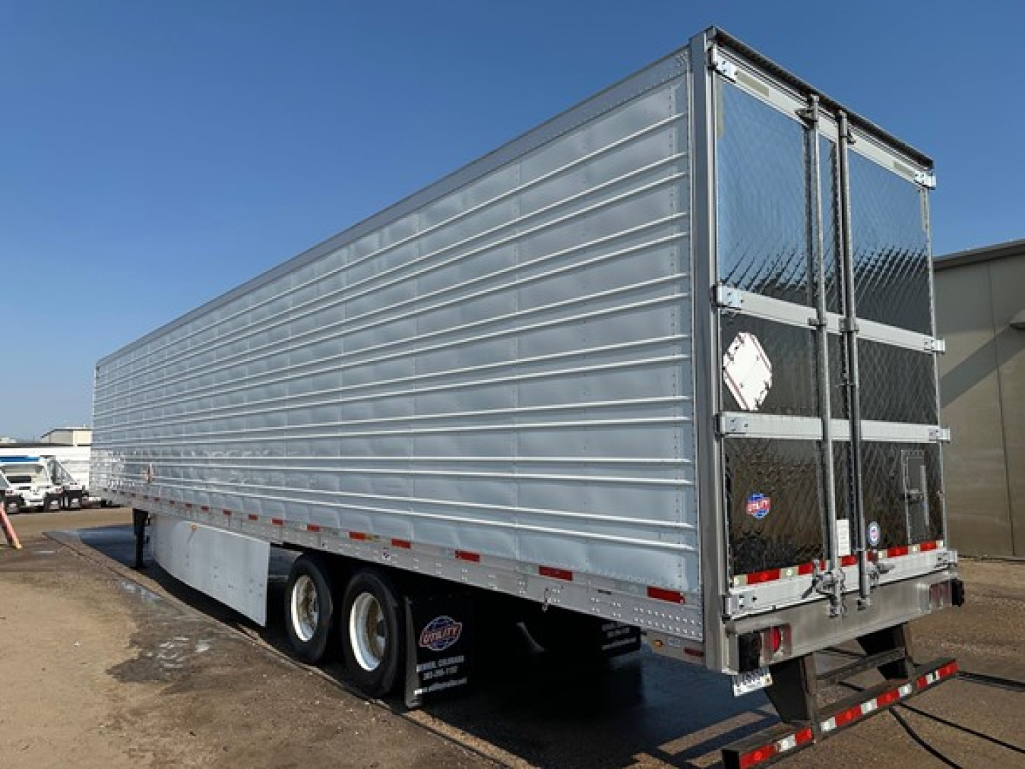 Trailer side and rear showing aluminum box truck trailer with dual rear doors and diamond plate end; three axles and reefer category trailer visible.