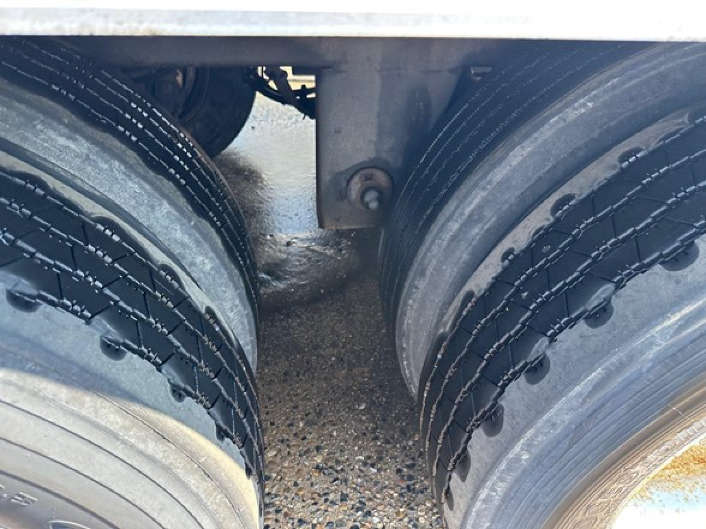 Trailer dual tires close-up view with chains around tires, showing wheel area and frame gap.