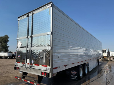 Utility trailer with aluminum sided reefer body, dual rear doors, and tandem axles.