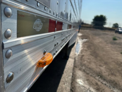 Reefer trailer side view showing Utility logo and reflective strips on aluminum siding with orange side marker light.