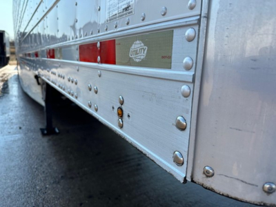 1980s Utility S-600 trailer side with riveted aluminum skin, reflective striping, Utility logo plate, near wheel arch and landing gear.