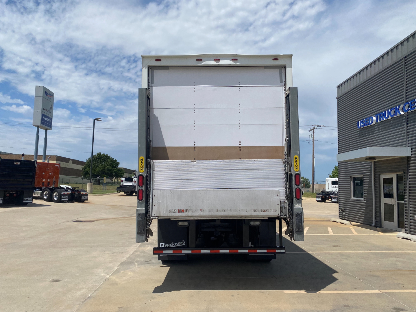 Back view of a white 2019 Mack AN64 box truck showing cargo doors and rear bumper with reflective tape.
