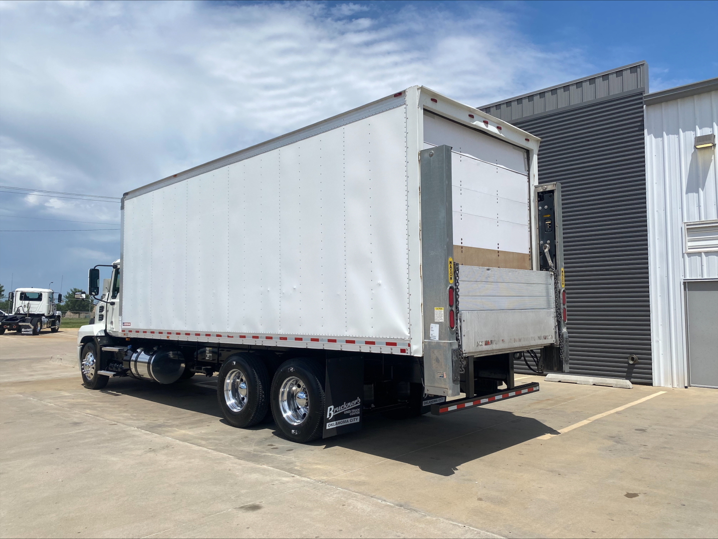 Box truck trailer attached to a Mack AN64 cab showing rear roll-up door and dual rear axles.