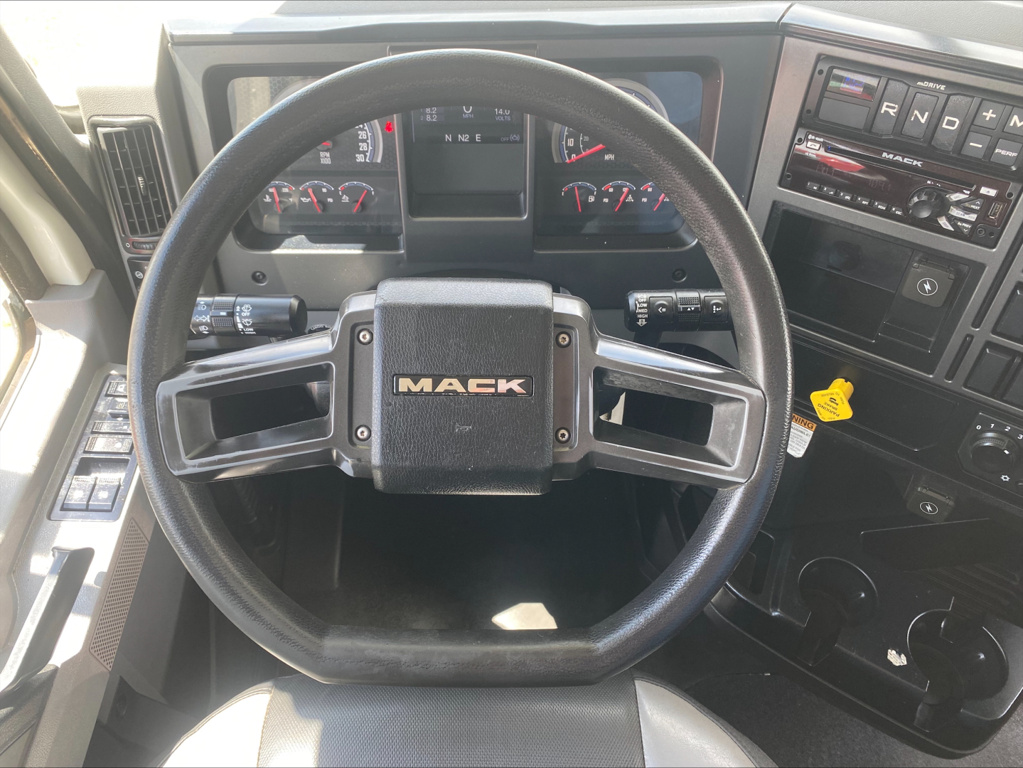 Mack AN64 truck interior showing steering wheel with Mack logo and dashboard controls.
