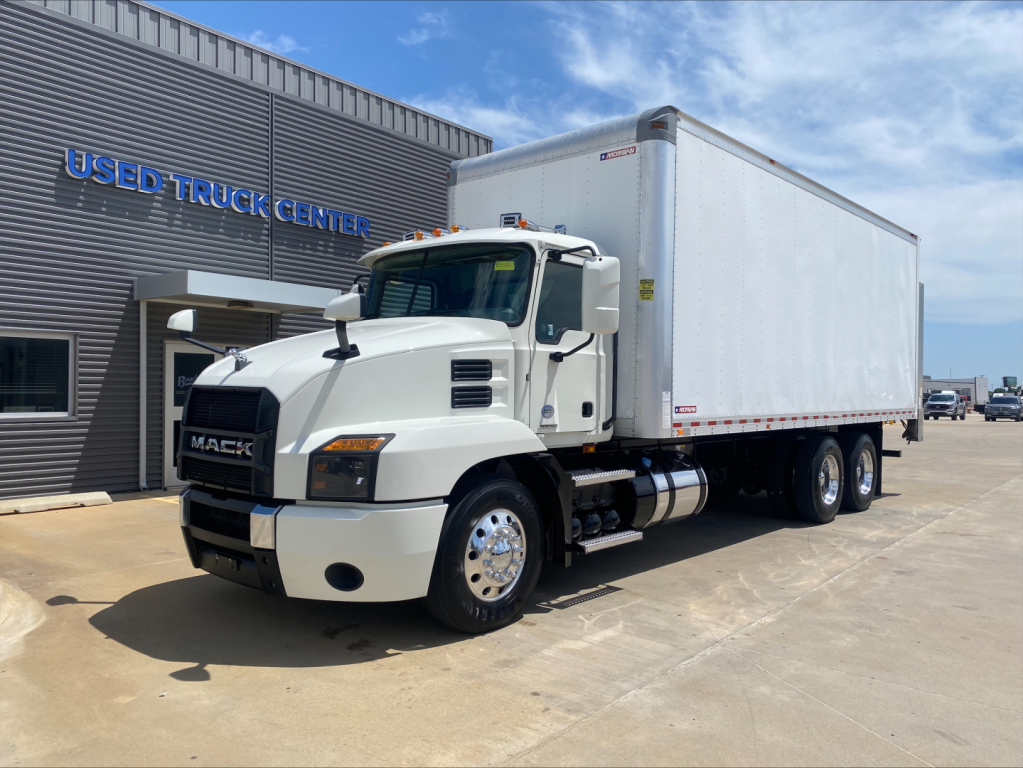 Mack AN64 dump truck in white with box trailer, front three-quarter view, parked outside Used Truck Center; visible Mack grille, cab, dual rear axles, box body.