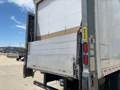 Box truck rear showing liftgate and closed sides with yellow MACKAXON label and rear lights.