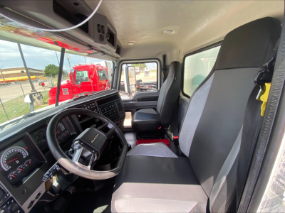 Front cab interior of a 2019 Mack AN64 truck showing steering wheel, dashboard, driver seat, and passenger seat.