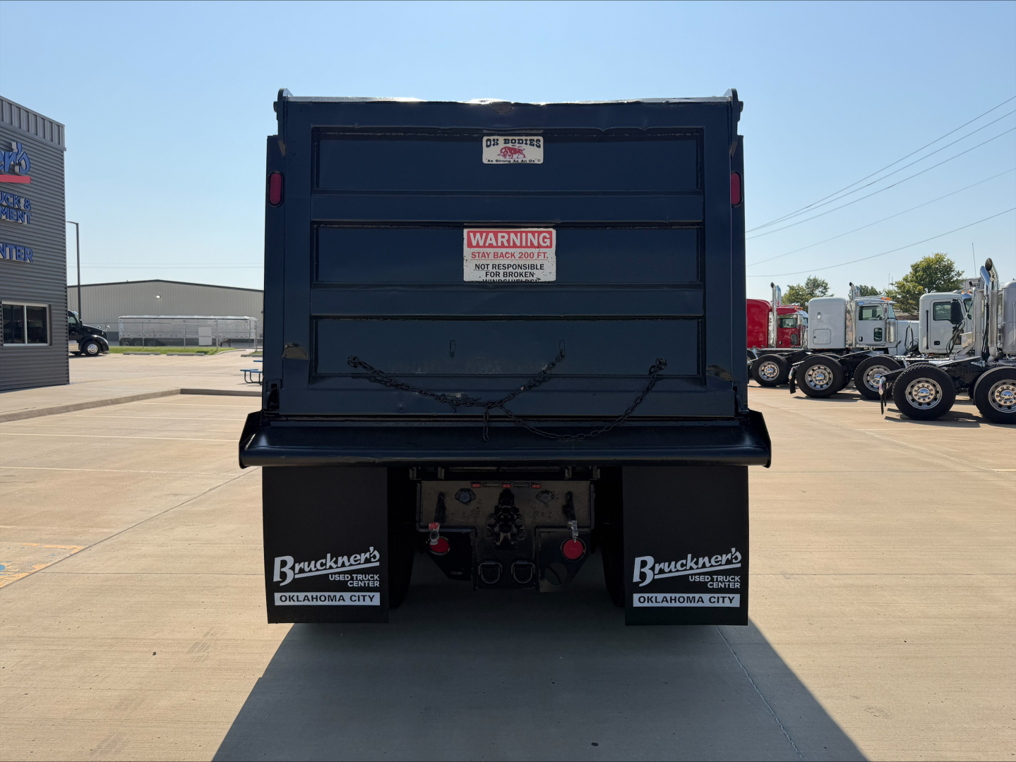 Dump truck bed of a 2020 Peterbilt 567 viewed from rear showing tailgate and warning sticker.